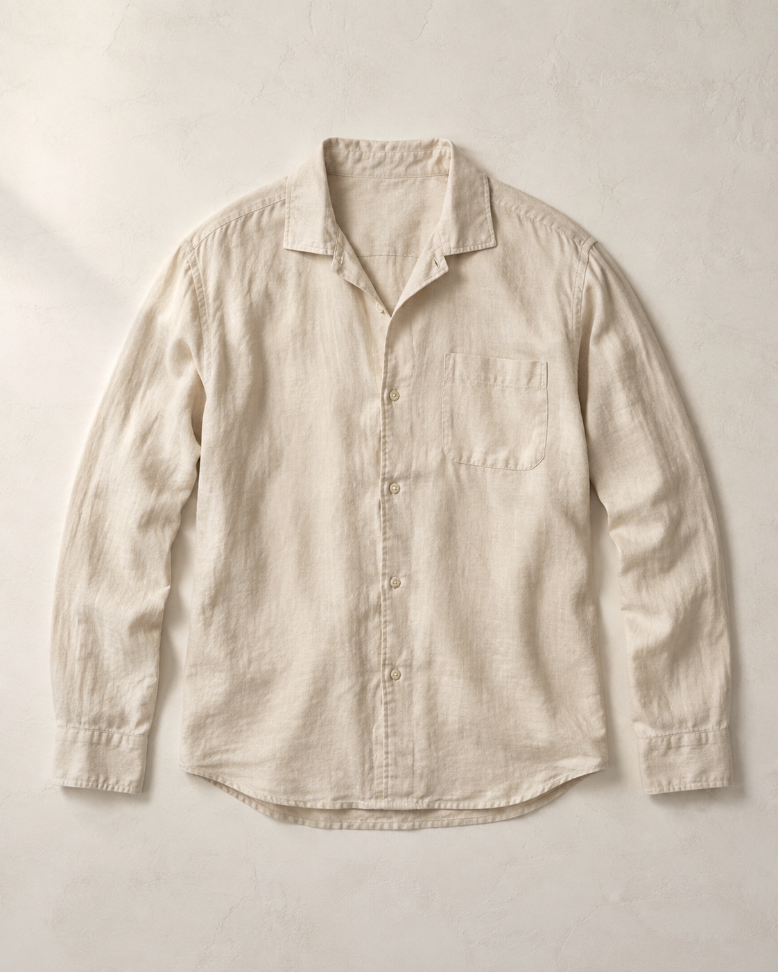 Unbranded pale linen shirt photographed flat on a warm neutral surface