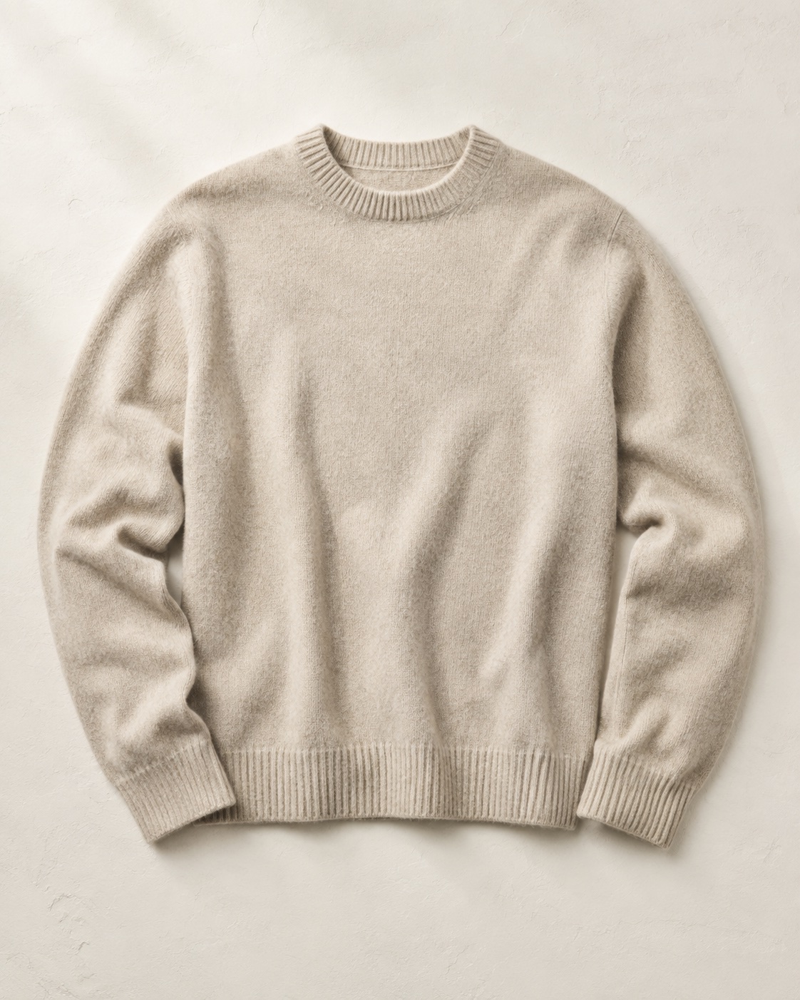 Unbranded oatmeal wool sweater photographed flat on a warm neutral surface